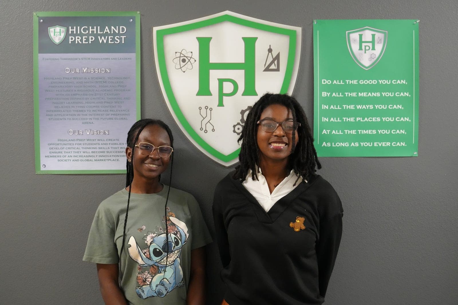 Two Highland Prep West students in front of the school mission wall